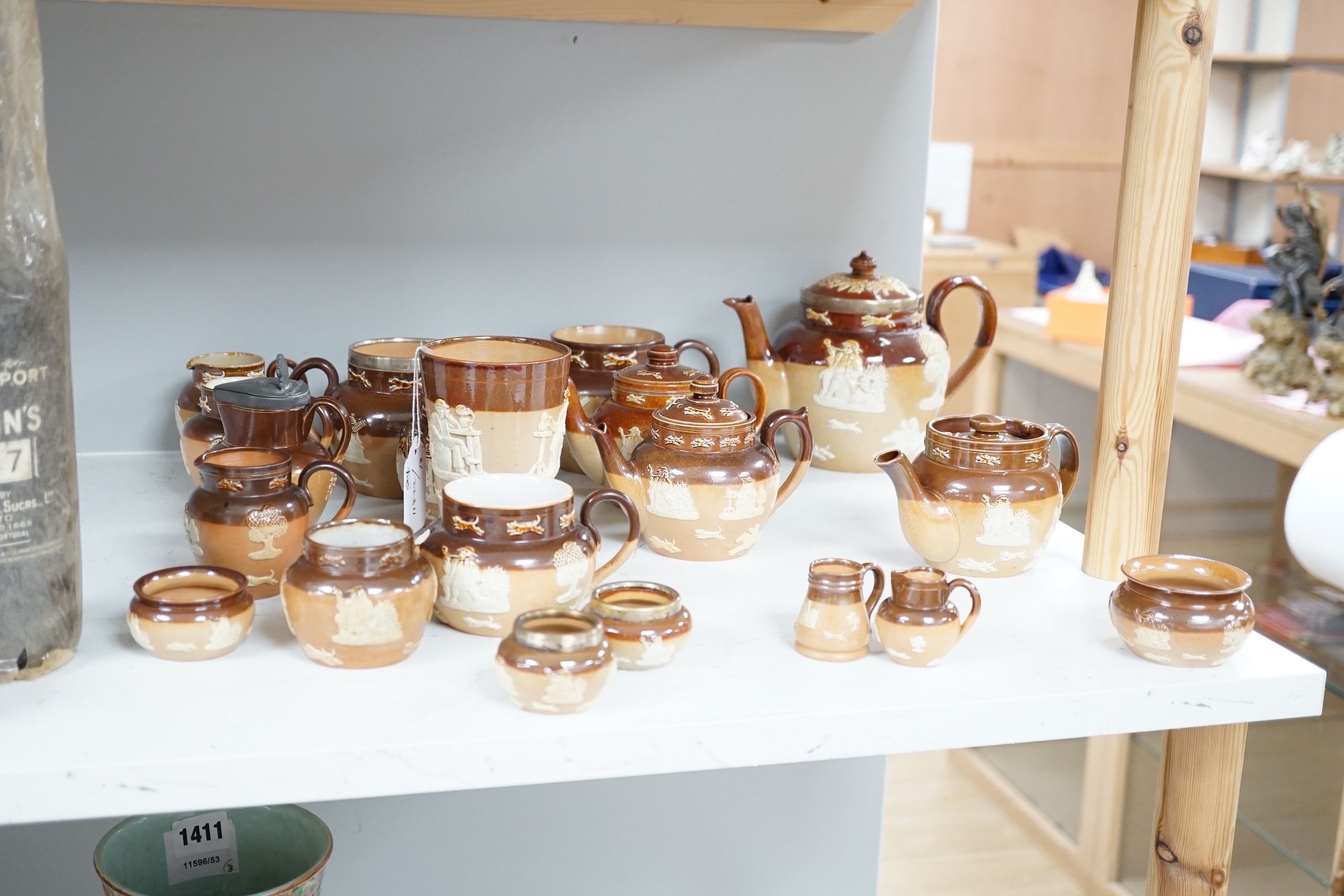 An assortment of Doulton stoneware including teapots, miniature tygs and twin handled pots, some silver mounted, largest 22cm wide